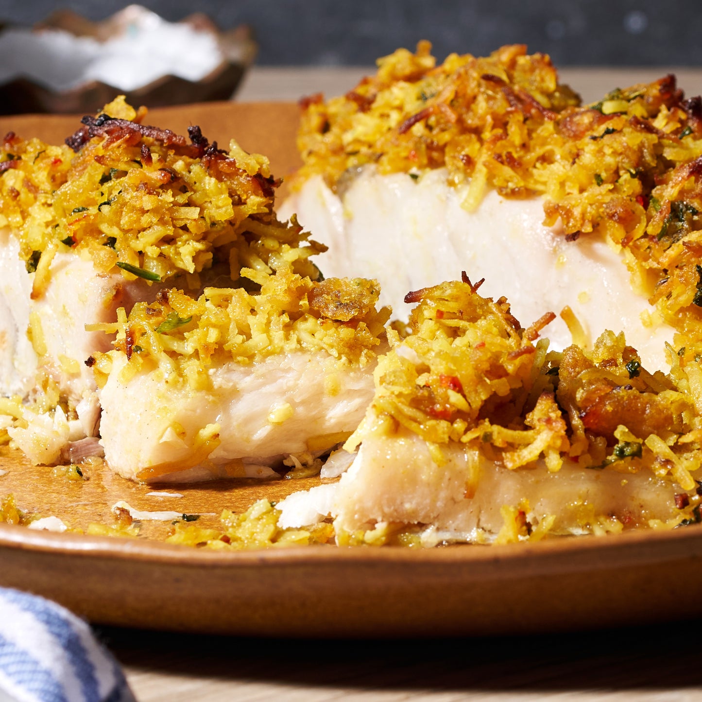Close-up of Coconut-Crusted Humpty Doo Barramundi showing tender white fish with a crisp toasted coconut and shallot topping.