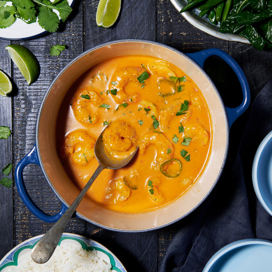 A pot of Goan prawn curry in a rich tomato, tamarind and coconut sauce, garnished with fresh coriander.