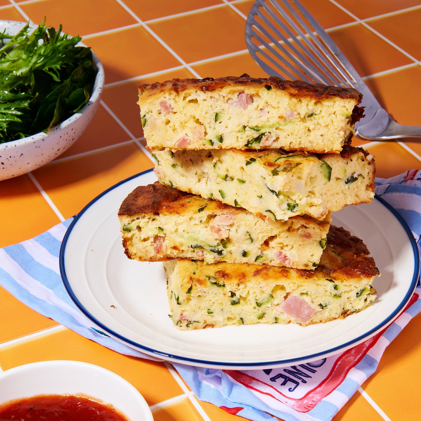 Thick wedges of zucchini and pancetta slice stacked on a plate, with a crisp golden crust and tender, cheesy filling inside.