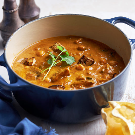 Blue pot of chickpea and eggplant coconut curry garnished with coriander.