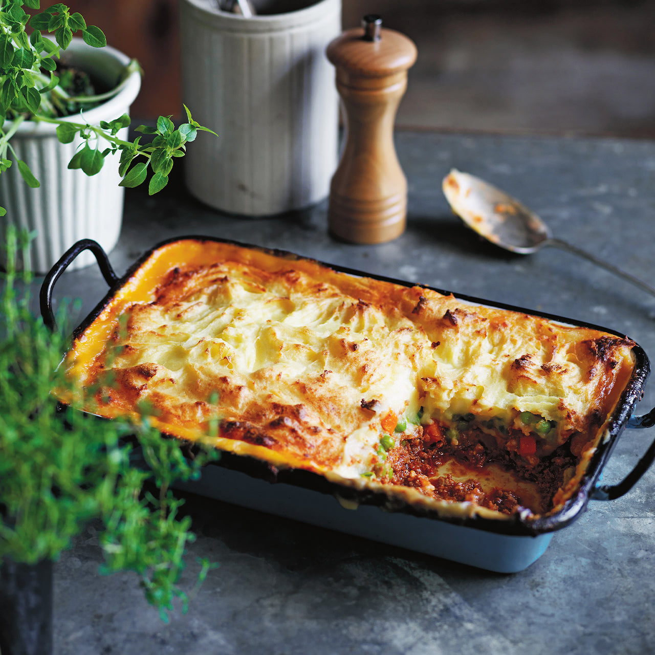 Cottage Pie in a tray with minced beef, peas and carrots, topped with golden buttery mashed potato.